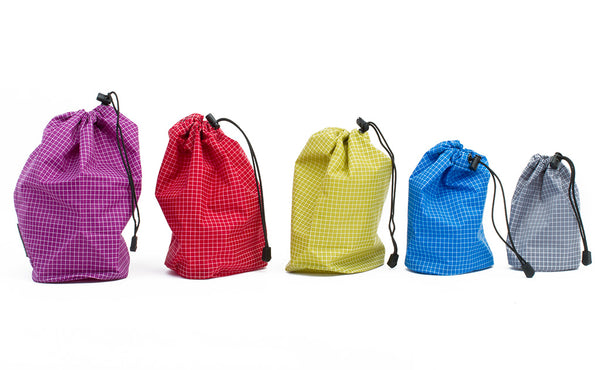 Each size of Travel Stuff Sack cinched closed and placed in a line from largest to smallest.
